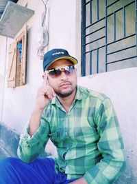 Young man wearing sunglasses standing against wall