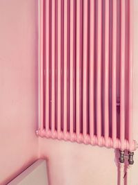 Close-up of pink radiator pipes on wall in building