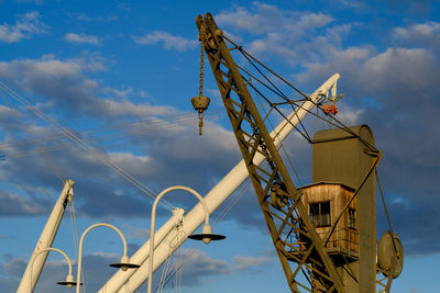 Low angle view of cranes at construction site against sky