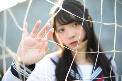 Portrait of young woman standing by sports net