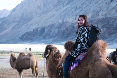 Portrait of woman riding animal against mountains