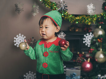 Cute baby girl holding christmas decoration at home