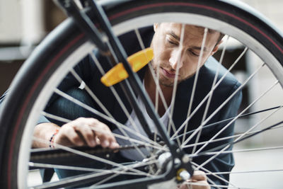 Businessman repairing bicycle tire on street
