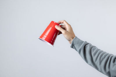 Close-up of hand holding red over white background