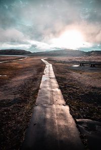 Footpath leading towards mountain against sky