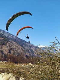 Low angle view of person paragliding against clear sky
