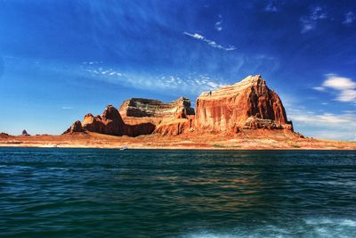 Rock formations by lake powell against blue sky