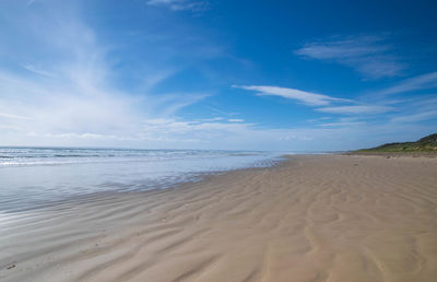 Scenic view of beach against blue sky