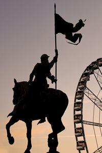 Low angle view of silhouette man riding statue