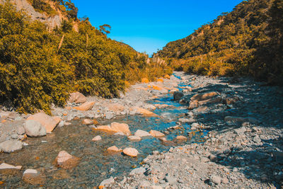 Low angle view of river flowing amidst rock formation against sky