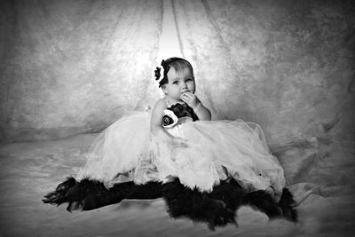 Portrait of cute girl wearing dress sitting on fabric