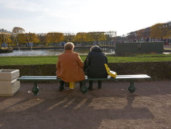 Rear view of people sitting on bench in park