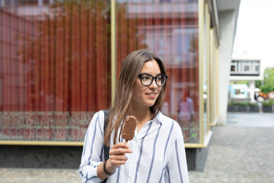 Portrait of young woman standing against wall