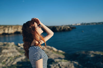 Young woman photographing sea against sky