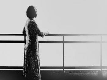 Rear view of woman standing by railing against sky