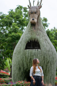 Portrait of woman standing by tree against plants