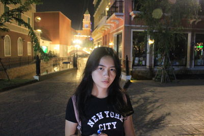 Portrait of teenage girl standing in city at night
