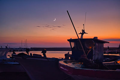 Silhouette boat on sea against sky during sunset with moon