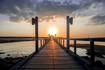 Pier over sea against sky during sunset
