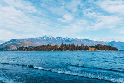 Scenic view of sea by mountains against sky