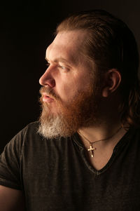 Portrait of man looking away against black background