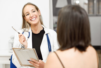 Smiling female doctor having discussion with patient at clinic