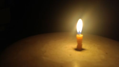 Close-up of lit candle in darkroom