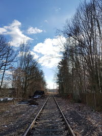 Railroad tracks amidst bare trees against sky