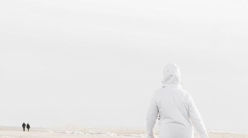 Rear view of man walking on snow covered landscape