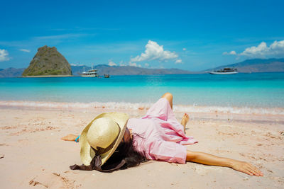 Woman sitting on beach against sky