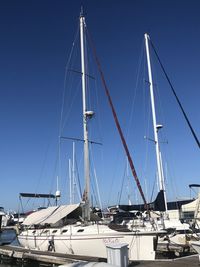 Sailboats moored at harbor against clear blue sky