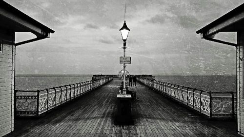 Railing by sea against cloudy sky