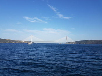 Suspension bridge over sea against blue sky