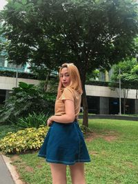 Portrait of young woman standing against trees