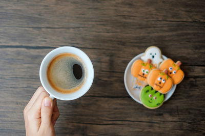 High angle view of hand holding coffee cup on table