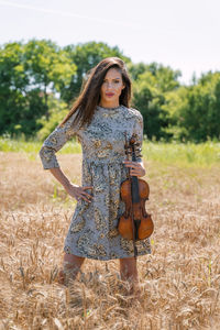 Portrait of a young woman standing on field