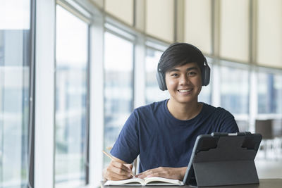 Portrait of a smiling young man sitting on window