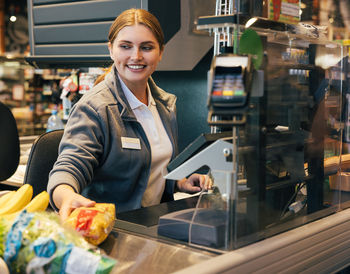 Portrait of smiling young woman holding food in store