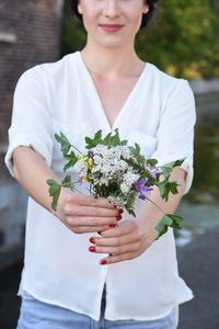 Midsection of young woman showing flowers on footpath