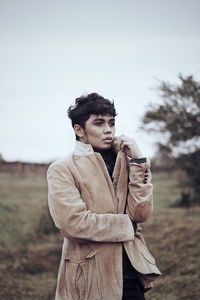 Thoughtful young man looking away while standing on field