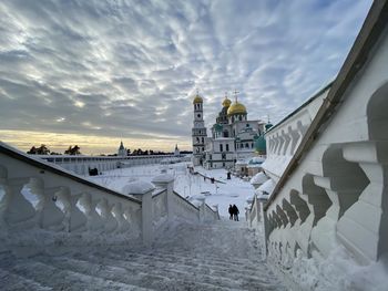 People on snow covered building against sky