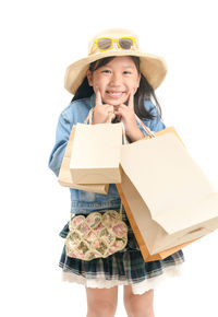 Portrait of smiling girl holding shopping bags standing against white background