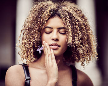 Close-up of young woman with curly hair holding flower