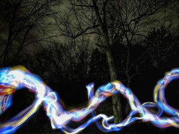 Close-up of illuminated bubbles against trees at night