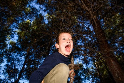 Low angle portrait of boy against trees