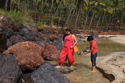 Rear view of people on rock against plants