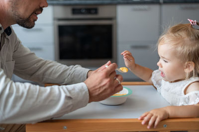 Midsection of mother and daughter sitting on table