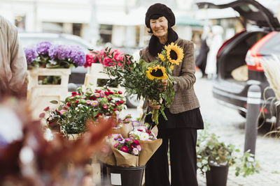 Smiling senior woman buying flowers from market