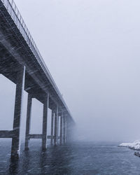 Silhouette bridge over sea against clear sky