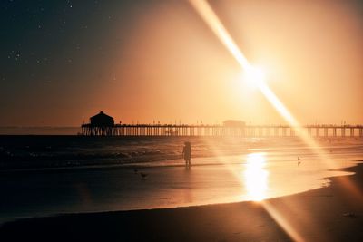 Silhouette pier on beach against sky during sunset